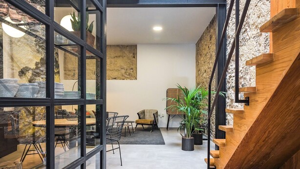 Um interior moderno com área de refeições, escada e vista para o exterior.