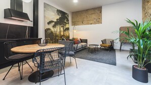 Um espaço de estar moderno com área de jantar, um sofá e uma grande pintura na parede.