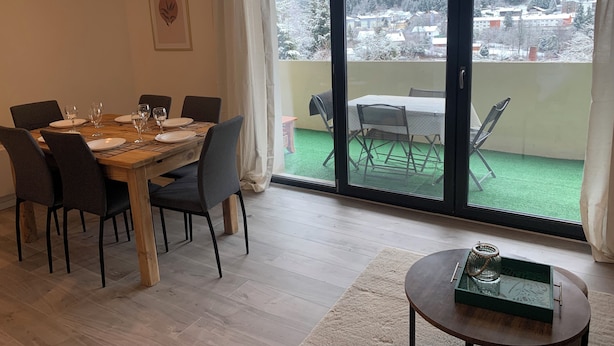 A dining area with a table set for four, a large window with a view of a snowy landscape, and a small side table with a tray.