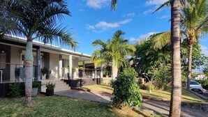 A modern house with a covered porch, palm trees, and a car parked in the driveway.