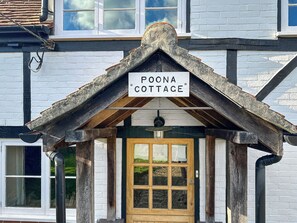 A traditional cottage with a sign reading "POONA COTTAGE" above the entrance. - 3 bedroom accommodation in Cadnam, near Southampton (Cadnam, near Southampton)