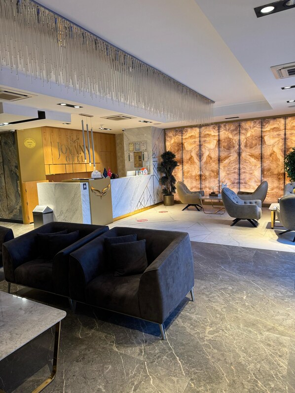 A modern hotel lobby with a reception desk, seating area, and a marble floor. - JOYANA OTEL (Çankiri)