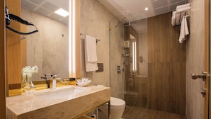 Une salle de bain moderne avec un meuble-lavabo en marbre, une douche à parois de verre et un lambris en bois.