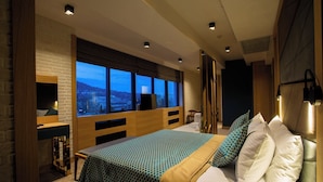 Une chambre d’hôtel moderne dotée d’un grand lit, d’un bureau et d’une grande fenêtre donnant sur la ville.