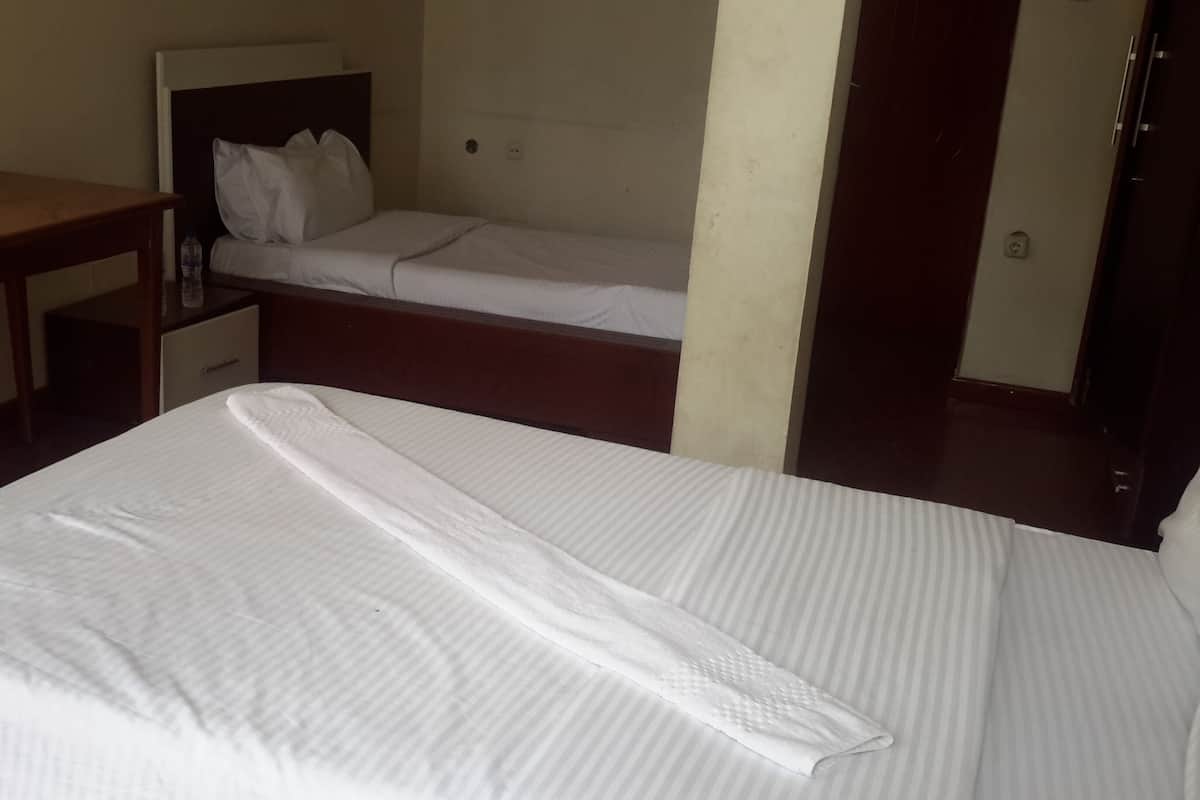 A hotel room with a large bed, a small desk, and a nightstand.