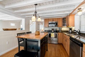 A modern kitchen with wooden cabinets, stainless steel appliances, and a wooden dining table. - Near Long Sands: 2 Living Areas, Family Fun (York)
