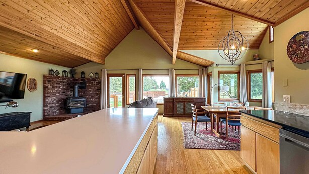 A spacious kitchen with a large island, wooden ceiling, and a dining area with a view of the outdoors.