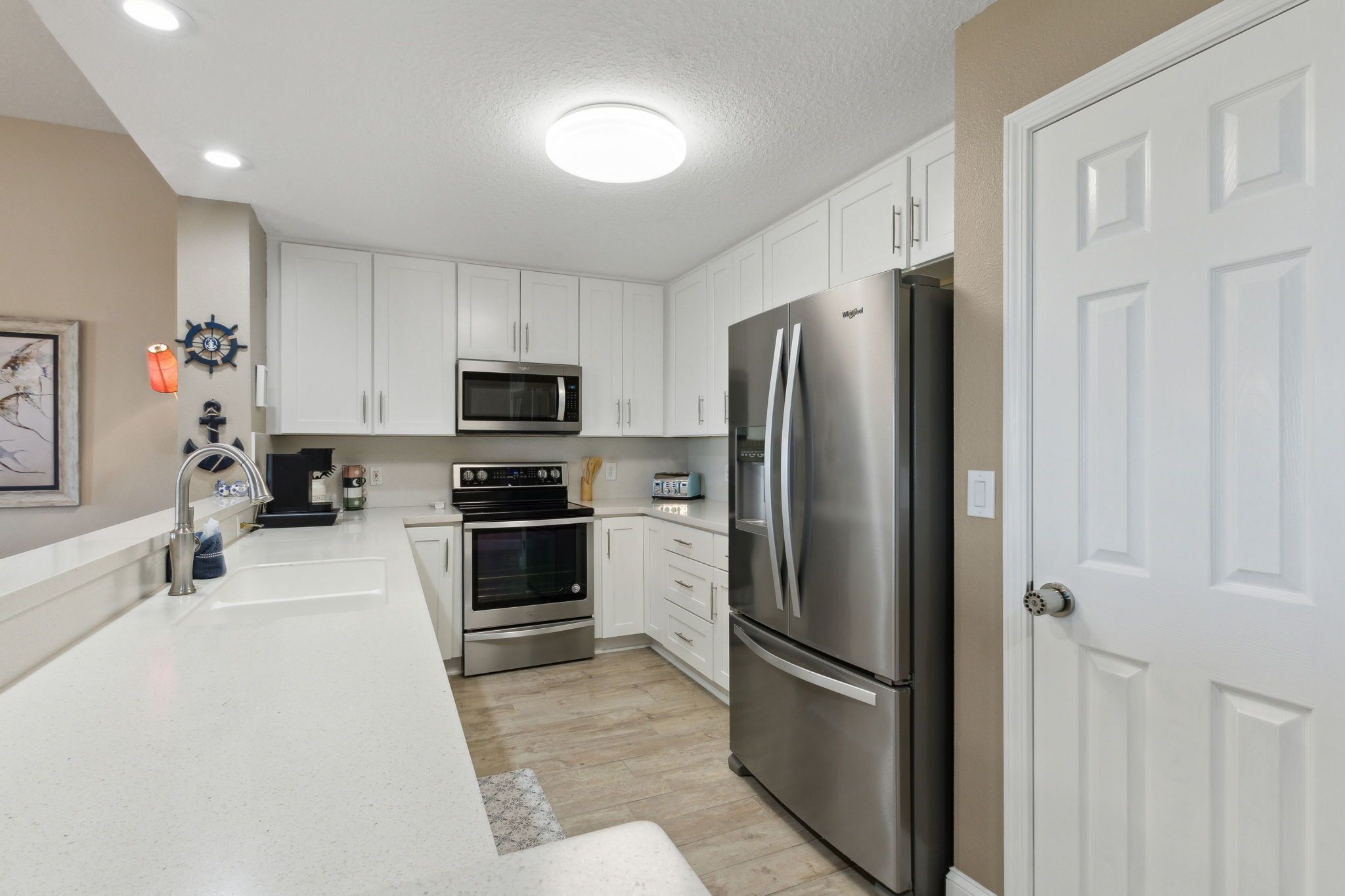 A modern kitchen with white cabinets, stainless steel appliances, and a white countertop.