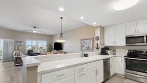 A modern kitchen with white cabinets, a stainless steel oven, and a large island with a sink. - Amelia Island 3 BR Ocean Park Beach Getaway (Fernandina Beach)
