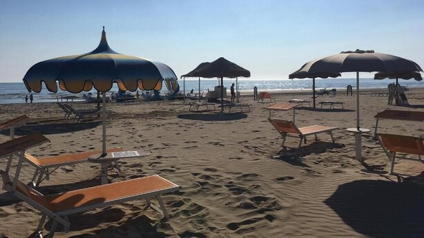 A beach with sun umbrellas, lounge chairs, and a clear view of the ocean. - Hotel Laura Beach (Rimini)