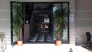 A hotel entrance with a checkered floor, two potted plants, and a sign reading "LAURA". - Hotel Laura Beach (Rimini)