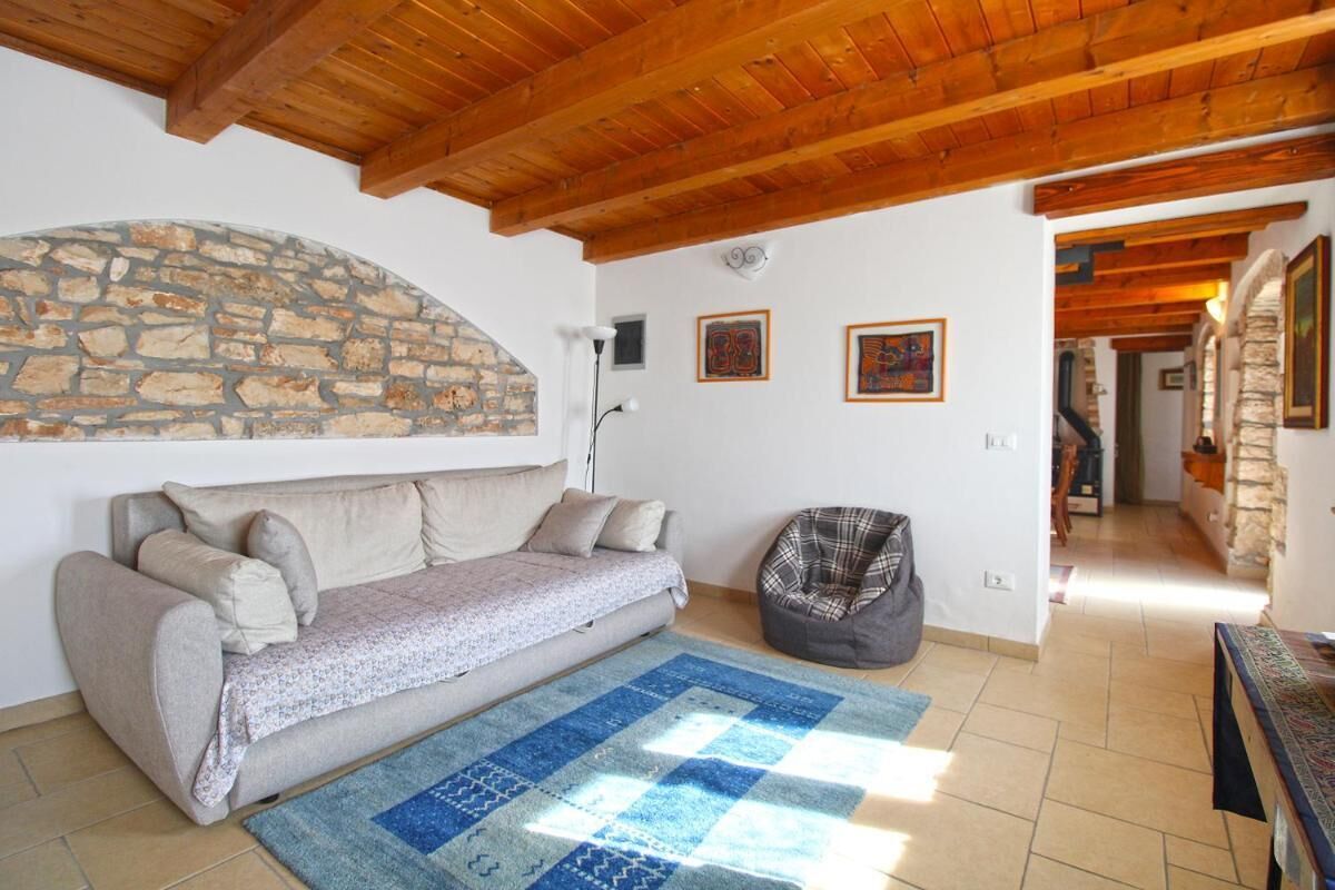 Uma sala de estar acolhedora com parede de pedra, um sofá, um bean bag e um tapete estampado.