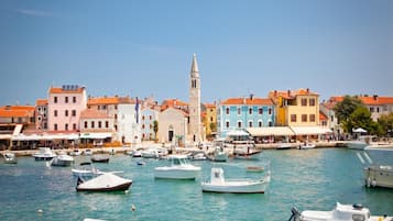A coastal town with colorful buildings, a prominent church with a bell tower, and numerous boats docked in the marina.