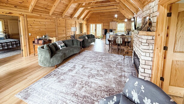 A log cabin interior with a living room, dining area, and kitchen.