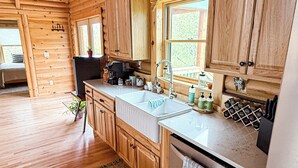 A wooden cabin interior with a kitchen area featuring wooden cabinets, a countertop, a sink, and a refrigerator.