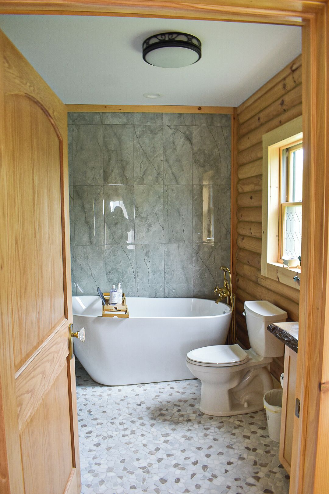 A bathroom with a freestanding bathtub, a toilet, and a vanity with a mirror.