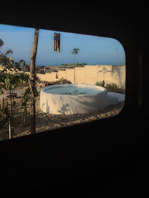 Guests can enjoy a serene view of a sandy area with a circular structure and palm trees.