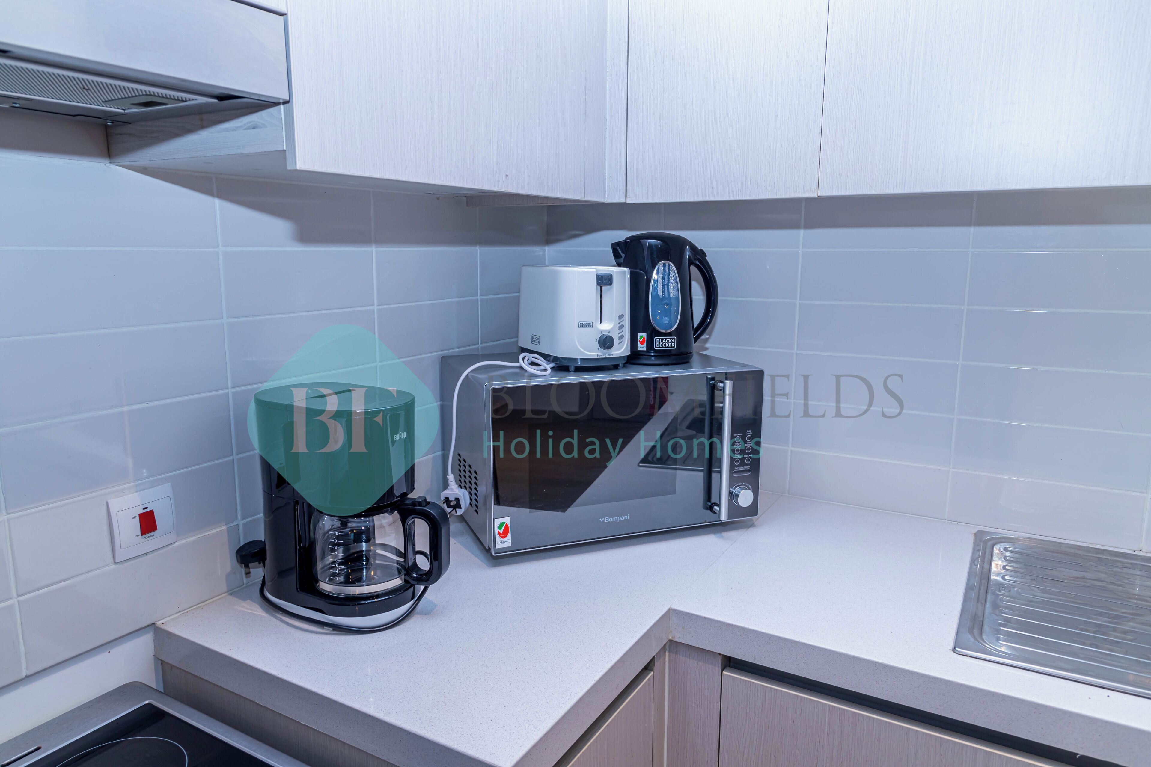 A kitchen with a coffee maker, a microwave, and a kettle on the counter.
