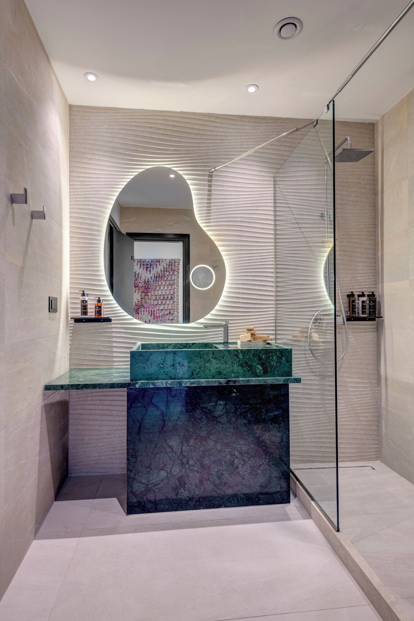A modern bathroom with a glass shower enclosure, a marble sink, and a unique wall design.