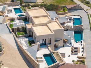 A modern resort with multiple swimming pools, stone pathways, and outdoor seating areas. - Pnoe Villas Syros (Syros)