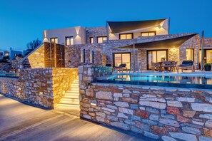 A modern house with a stone exterior, a swimming pool, and outdoor seating.
