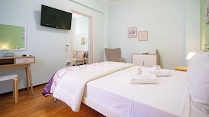 A hotel room with a bed, a desk, a chair, a television, and a wardrobe.