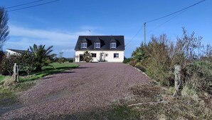 Een huis met twee verdiepingen en een grindpad dat naar de voordeur leidt.