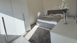 Una camera da letto moderna con un letto, un comodino, un vaso con fiori e una lampada a soffitto.