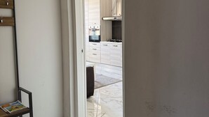 Un corridoio con una porta bianca che dà su un angolo cottura.