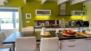 Una cocina moderna con comedor, que cuenta con una mesa grande, sillas blancas y una pared de color verde brillante.