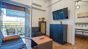 Un salon moderne comprenant un canapé, une table basse, un téléviseur et une porte-fenêtre coulissante donnant sur un espace extérieur.