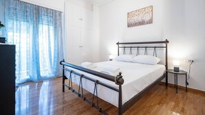 Une chambre bien rangée, avec un lit, des tables de chevet, une armoire et une fenêtre avec des rideaux.