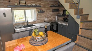 Une cuisine moderne dotée d’un four encastré, d’une table à manger agrémentée d’un panier de fruits et d’un escalier en bois.
