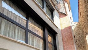 A modern building with a large garage door, a small window, and a brick wall. - La Grange, in the heart of the village (Argelès-sur-Mer)