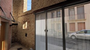 A courtyard with stone walls, a metal gate, and a car in the background. - La Grange, in the heart of the village (Argelès-sur-Mer)