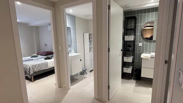 A modern hotel room with a bed, a bathroom with a mirror, and a small seating area. - La Grange, in the heart of the village (Argelès-sur-Mer)