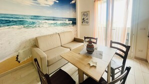 Une pièce décorée d’une fresque représentant une plage, avec un canapé, une table à manger et une chaise.