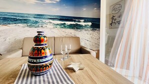 Une pièce avec vue sur l’océan, un vase décoratif, deux verres et une nappe à rayures.