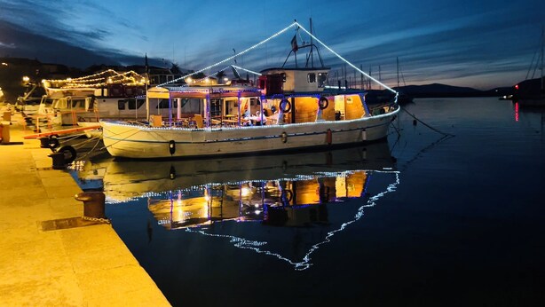 Un bateau était amarré dans une marina, avec un espace de repos abrité et des lumières qui se reflétaient sur l’eau.