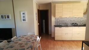 Un espace de vie compact comprenant un coin repas, une kitchenette et un téléviseur.