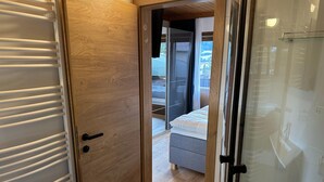Un dormitorio moderno con puerta de madera, cama y vistas a un balcón.