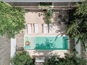 An aerial view of a rooftop pool area with lounge chairs, a small inflatable pool, and surrounding greenery. - Villa Sorella (Tulum)