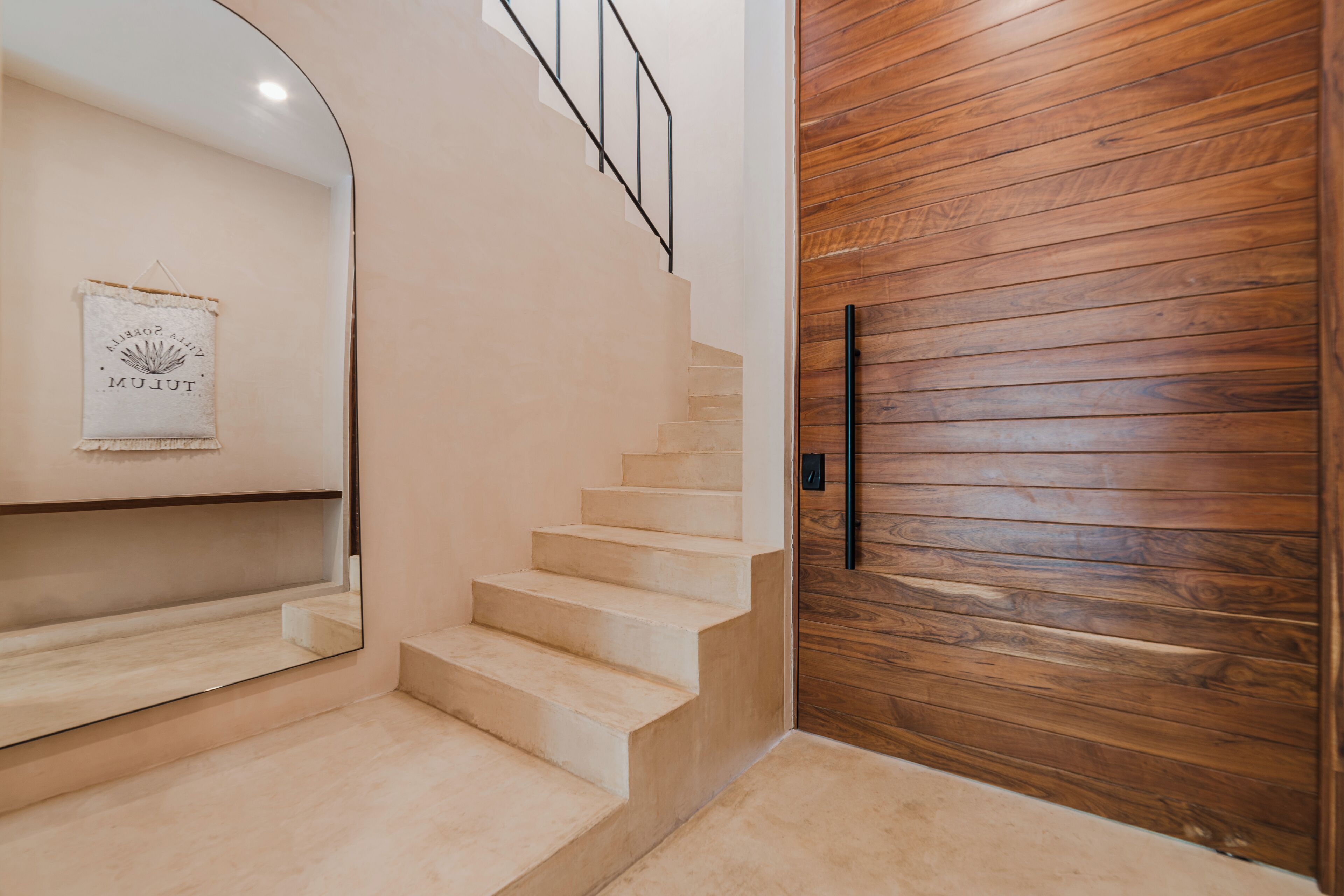 Una escalera con detalles de madera, un espejo en la pared y un letrero enmarcado.