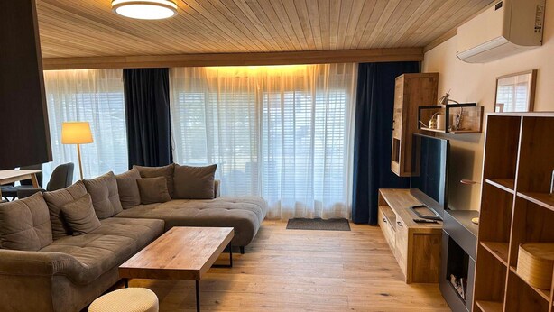 Un salon moderne avec un canapé d’angle, une table basse en bois et un meuble pour la télévision.
