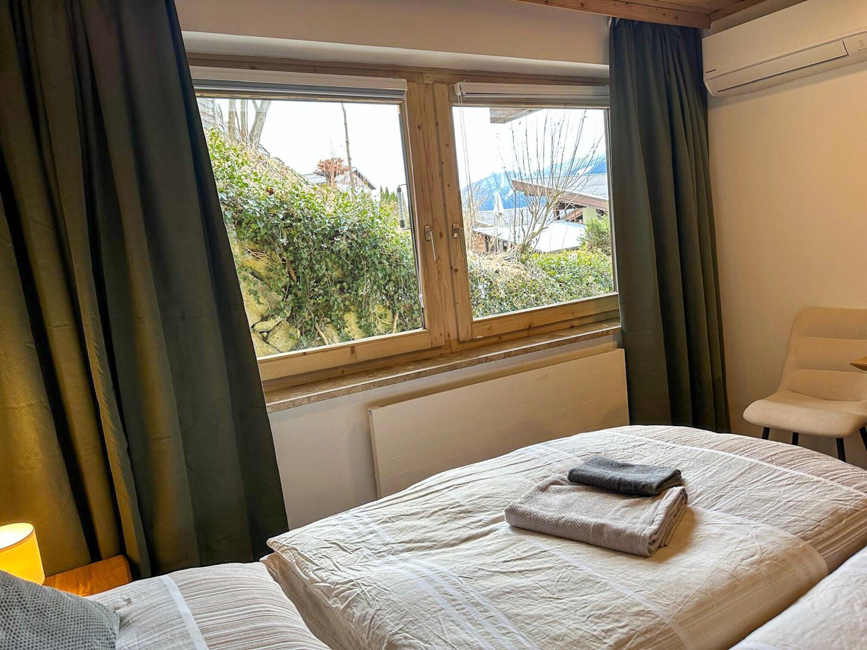 A bedroom with a bed, a chair, and a window with curtains.