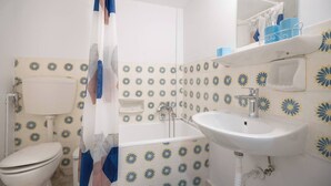 Een badkamer met toilet, wastafel en bad.