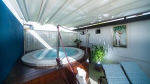 A hot tub area with a wooden deck, a covered seating area, and a potted plant. - Hotel Erika (Rimini)