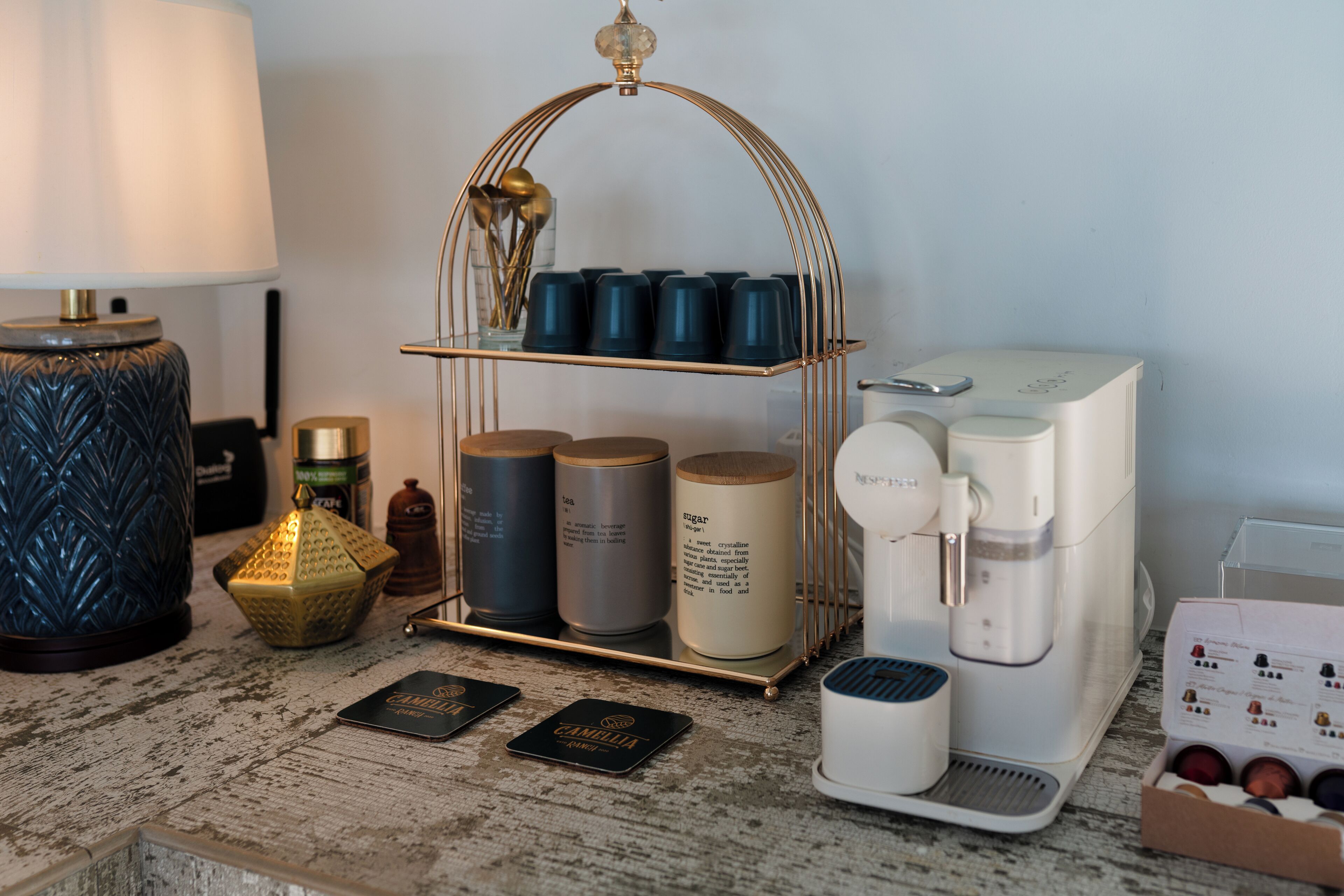 Un plan de travail de cuisine avec une machine à café, un étagère à épices et une lampe décorative.