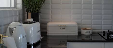 A kitchen with a bread box, a cheese container, and a potted plant.