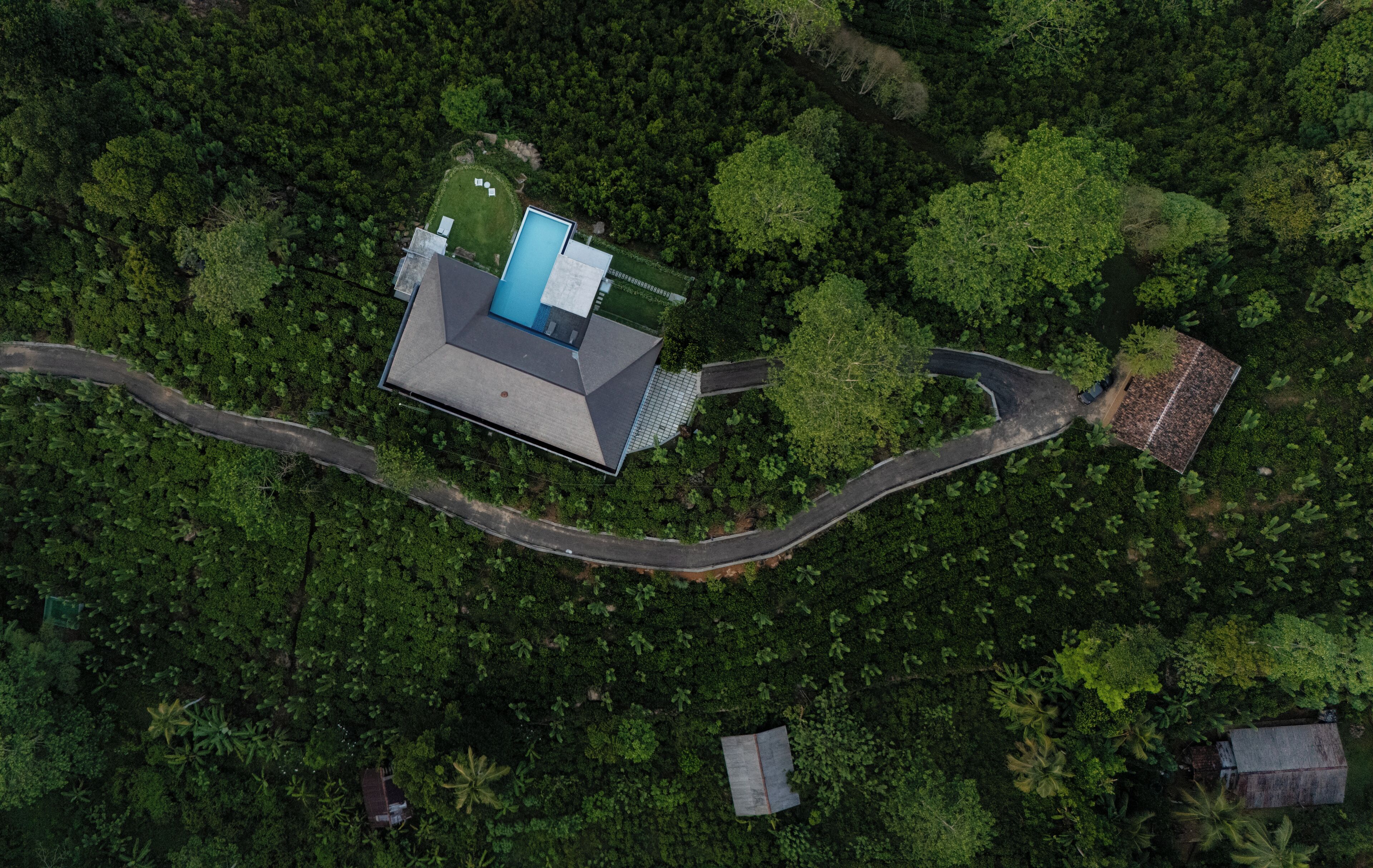 Ein Luftbild eines modernen Hauses mit Schwimmbad, umgeben von dichtem Wald.